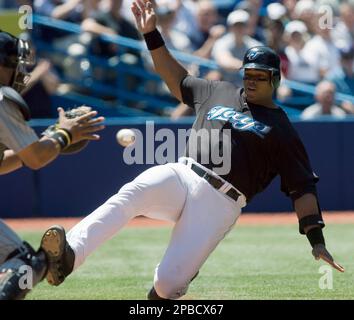 Toronto Blue Jays' Frank Thomas, right, watches the ball arrive in the mitt  of Colorado Rockies catcher Yorvit Torrealba as he slides into home plate  during third inning interleague action in Toronto