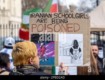 A protester in London holds a placard highlighting the Iranian Regime is poisoning schoolgirls, protest banner, 11th March, 2023, England, UK.