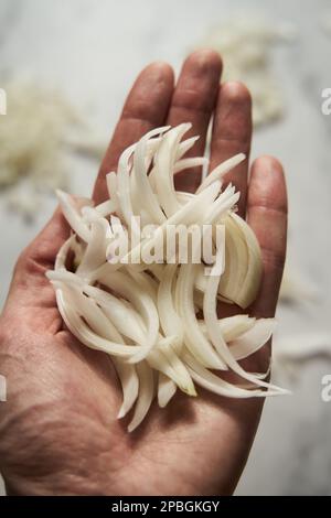 Julienne cuted onions on mans hand. Photo show how does julienne sliced or pole to pole to root to stem or half rings onions look like Stock Photo
