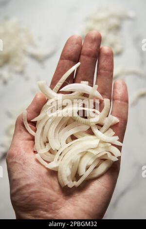 Julienne cuted onions on mans hand. Photo show how does julienne sliced or pole to pole to root to stem or half rings onions look like Stock Photo