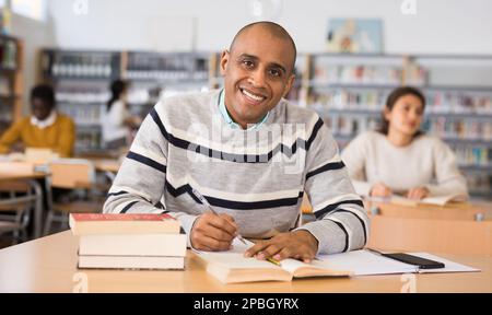 Cheerful adult hispanic student studying in university library Stock Photo