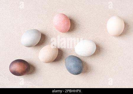 Natural dyed Easter eggs on beige table. Eco, pastel pale colors. Stock Photo