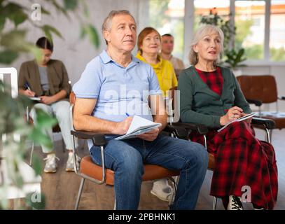 Group of older students sitting and listening at lesson Stock Photo