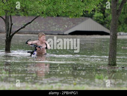 An unidentified youth pushes his bicycle in floodwaters in