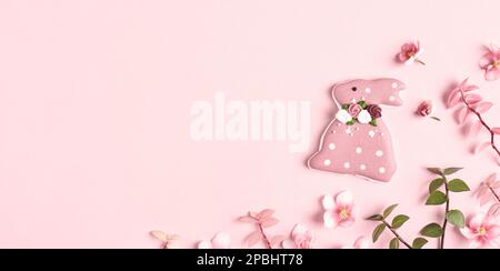 Happy Easter banner. Easter decorations, bunny, grass and flowers on pink background. Copy space, flat lay. Stock Photo