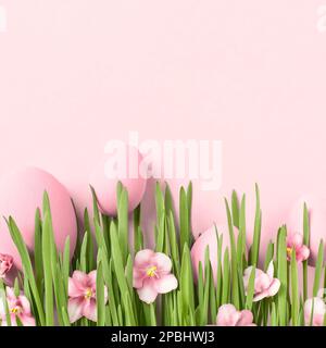 Easter background. Easter eggs in grass with pink flowers. Floral Easter greeting card, copy space, pastel colors. Stock Photo