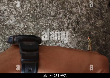 miniature figure of a worker walking on human hands. Stock Photo