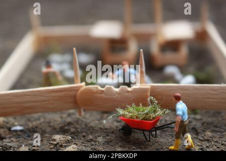 A close up of miniature figure of a goat herder feeding in a wooden cage. Shepherd concept. Stock Photo