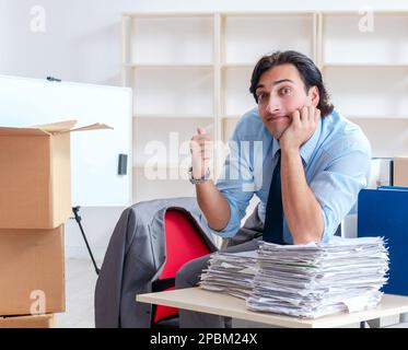 The young man employee with boxes in the office Stock Photo