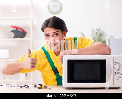 The young repairman repairing microwave in service centre Stock Photo