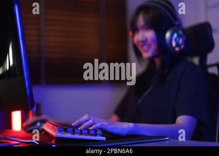 Female cyber hacker gamer in headphone serious face to playing games or hacking programming system. Stock Photo