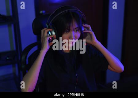Female cyber hacker gamer in headphone watching video game on monitor to hacking programming system. Stock Photo