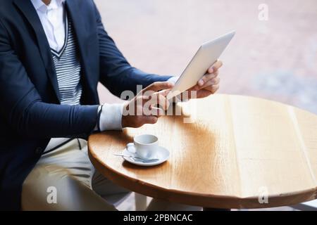 Working in the cafe. Cropped image of a man surfing the net on his digital tablet. Stock Photo