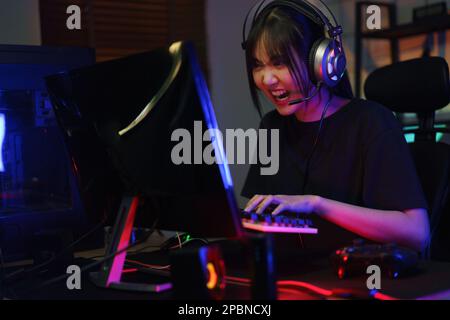 Female cyber hacker gamer serious face while pressing on keyboard to competition and playing games. Stock Photo