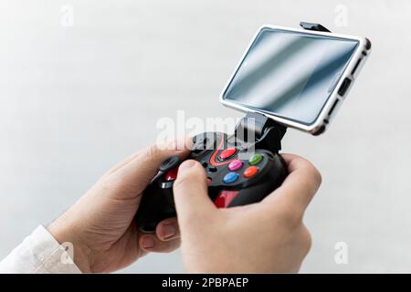 Man playing on smartphone. a joystick connected to a smartphone wirelessly. The game is on the phone. Stock Photo