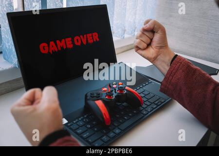 Game over on laptop screen. losing a video game. joystick on the keyboard. gestures. Stock Photo