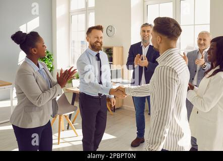 Happy business teams making a deal, showing recognition to each other, and exchanging handshakes Stock Photo