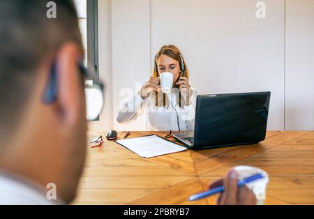 Woman with headset in customer help service taking a break and drinking cup of coffee Stock Photo