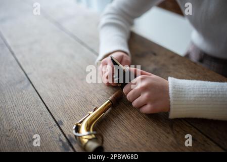 Young woman putting the mouthpiece on a saxophone to start playing Stock Photo