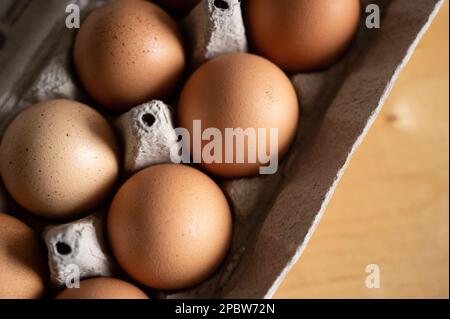 Close up of a carton of brown organic eggs on wood kitchen table Stock Photo