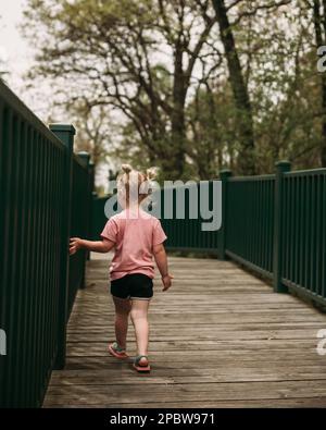 Young child walking on bridge during nature walk Stock Photo