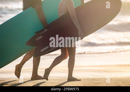 Surfers carrying surf boards walking the beach in Bali, Indonesia. Stock Photo