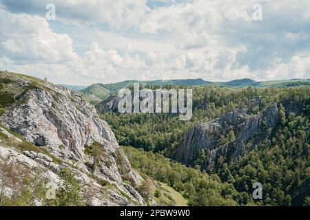 mountain valley covered with coniferous forest, cloudy sky Stock Photo