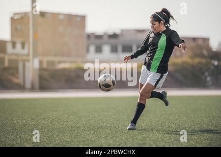 Young female soccer player kicking ball in a stadium. Stock Photo