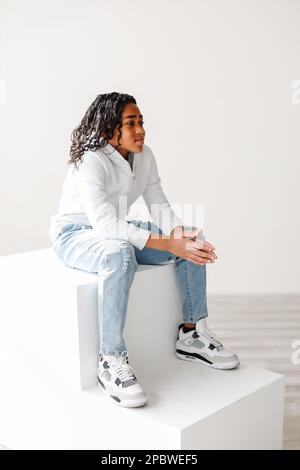 Mixed-race brown boy with long curly hair sitting inside on steps Stock Photo