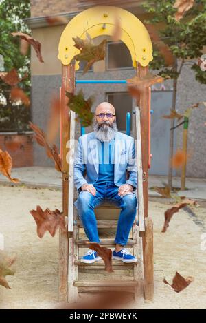 middle-aged, balding, bearded man sitting in a park relaxing Stock Photo