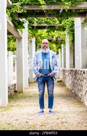 man posing standing with his hands in his pockets in a city park. Stock Photo