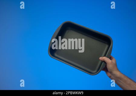 https://l450v.alamy.com/450v/2pbwkw9/black-nonstick-empty-rectangular-oven-tray-held-by-caucasian-male-hand-close-up-studio-shot-isolated-on-blue-background-2pbwkw9.jpg