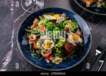 salad with quail eggs, bacon, vegetables, herbs and sauce Stock Photo