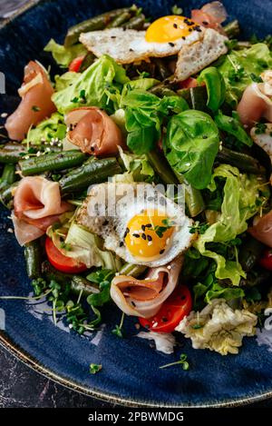 salad with quail eggs, bacon, vegetables, herbs and sauce Stock Photo