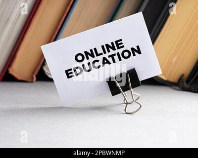 The word online education written on a business card with books background. Stock Photo