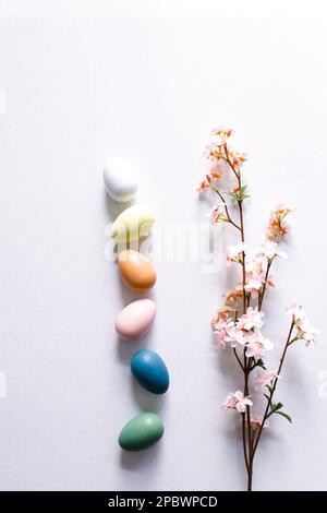 Spring flowers and colorful chicken eggs flat lay on white desk Stock Photo