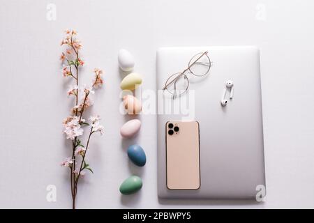 Spring flowers, colorful eggs, closed laptop, phone, earbuds Stock Photo