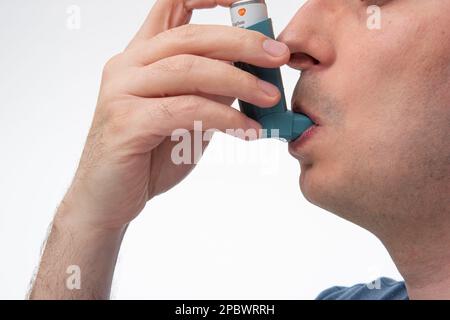 Asthma inhaler, generic, non-branded, being used by unrecognizable by man. Close up studio shot, isolated on white background. Stock Photo