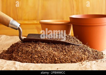 Dry coconut fibre substrate made eco-friendly and cheap from coco coir bricks, ready to use as grow or potting soil, with a trowel and empty pots. Stock Photo