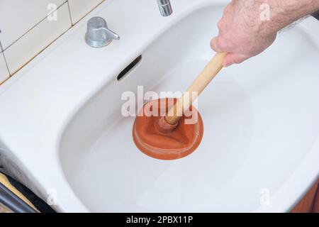 https://l450v.alamy.com/450v/2pbx11p/caucasian-male-hand-holding-a-plunger-unclogging-a-bathroom-sink-2pbx11p.jpg