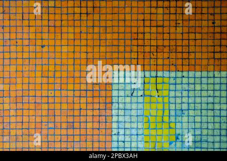 Colored ceramic tiles mosaic wall. Close up shot of old textured square patterns tiles, front view, no people. Stock Photo