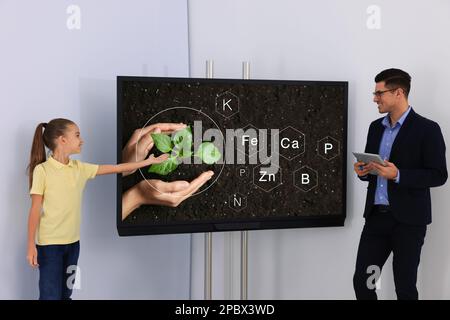 Teacher and pupil using interactive board in classroom during lesson Stock Photo