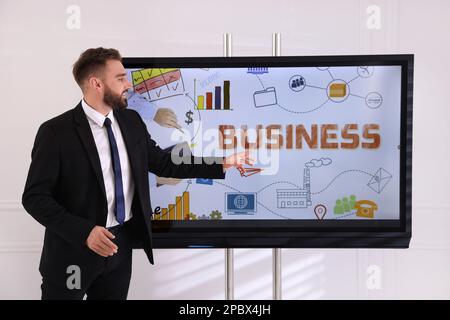 Business trainer using interactive board in meeting room Stock Photo