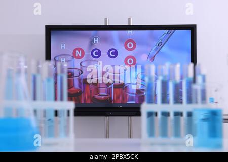 Modern interactive board and laboratory glassware in classroom Stock Photo