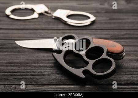 Black brass knuckles and knife on wooden background, closeup Stock Photo -  Alamy