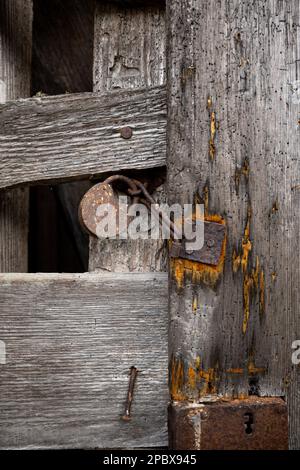 Old rusted iron lock on a wooden barn door. Close up shot, no people. Stock Photo