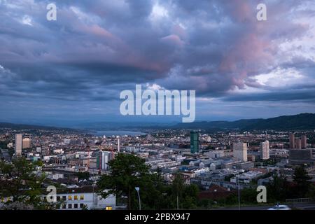 High overview of Zurich city Switzerland at dusk. Evening light, pink clouds, moody atmosphere, top view, vista point, no people. Stock Photo