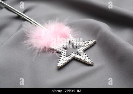 Beautiful silver magic wand with feather on grey fabric, closeup Stock Photo