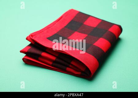 Folded red checkered bandana on turquoise background Stock Photo
