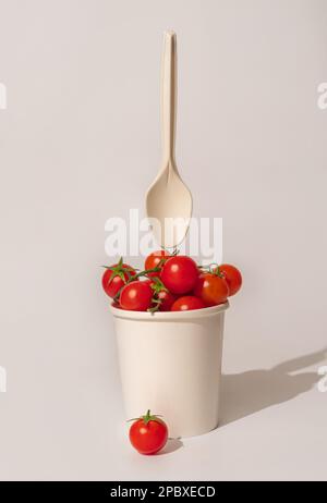 Fresh cherry tomatoes in a paper cup on light background. Stock Photo